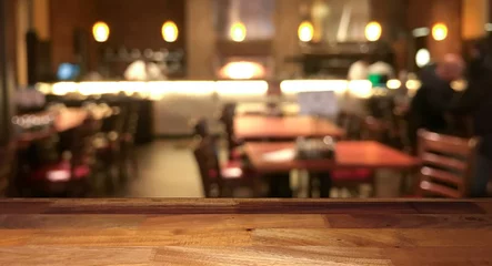 Rolgordijnen Empty wooden table top with blurred restaurant on background © Nuli_k