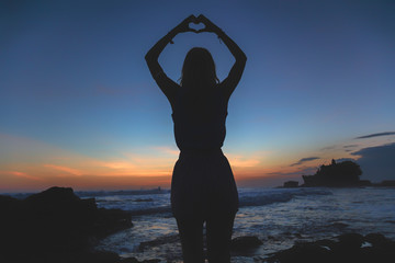 Fototapeta premium Girl holding a heart shape on the ocean / sea shore.