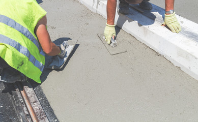 Construction worker leveling concrete pavement outdoors.
