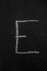 Letter E drawn with white chalk on blackboard. Education, school concept