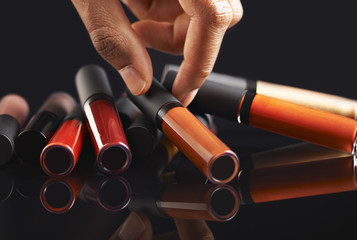 Fototapeta premium Hand holding a liquid lipstick on black background