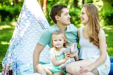 Mother, father and little daughter at a picnic in the park. The concept of family, lifestyle and children.