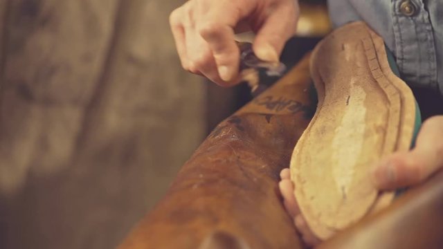 Cropped video of young shoemaker in workshop making shoes
