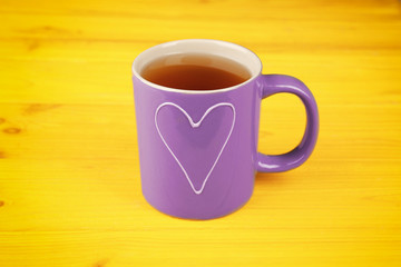 Lilac cup with tea on yellow background