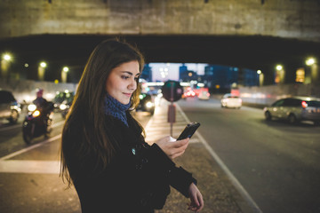 YOung woman outdoor using smart phone hand hold face illuminated by screen light - social network,...