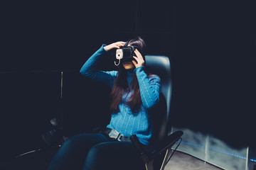 Young beautiful eastern woman sitting on a gaming chair testing augmented reality with 3D viewer - games, futuristic, augmented reality concept
