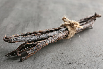 Dried vanilla sticks on grey textured background, closeup