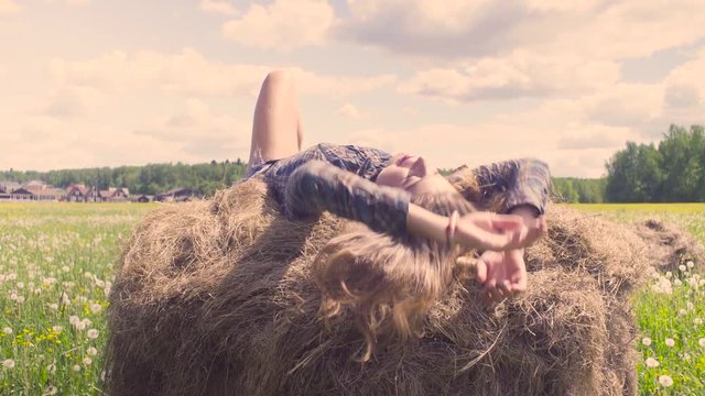 Young woman laying on haystack at summer