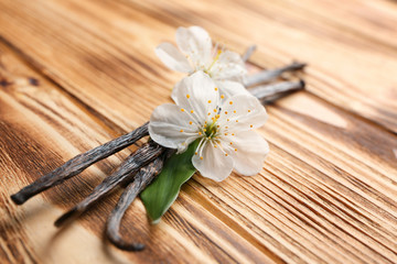 Dried vanilla sticks and flowers on wooden background, closeup