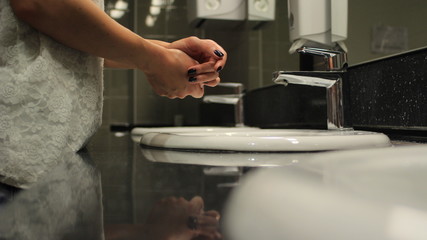 female hands over the sink in a public restroom