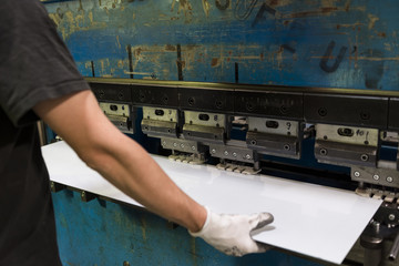 Worker bending a sheet of aluminium. - obrazy, fototapety, plakaty
