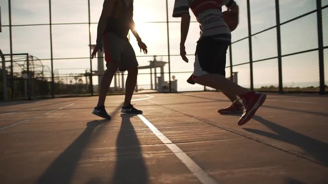 Group of Caucasian males playing streetball dribbling passing having fun. Footage in slowmotion with sun flare