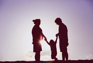 happy family play with little daughter at sunset