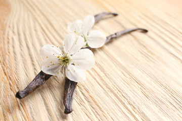 Dried vanilla sticks and flowers on wooden background, closeup