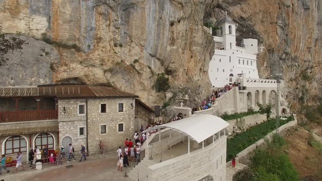 Unique old Ostrog white Monastery in the rock central Montenegro nature. Famous tourist religion Orthodox Church. Aerial drone flight around. Summer day