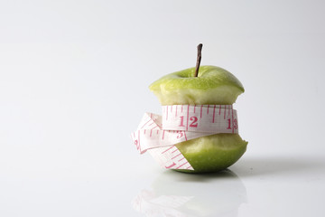 Close up of green apple with measuring tape isolated on white background.