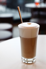 A glass latte macchiato in the cafe, the background with sharpening depth