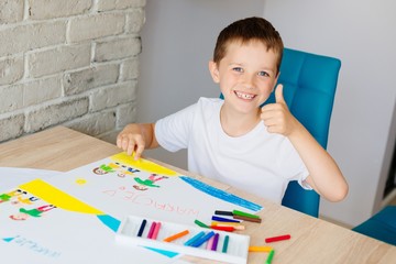 Dziecko maluje pastelami obrazek przedstawiający szczęśliwą rodzinę na plaży © Daniel Jędzura