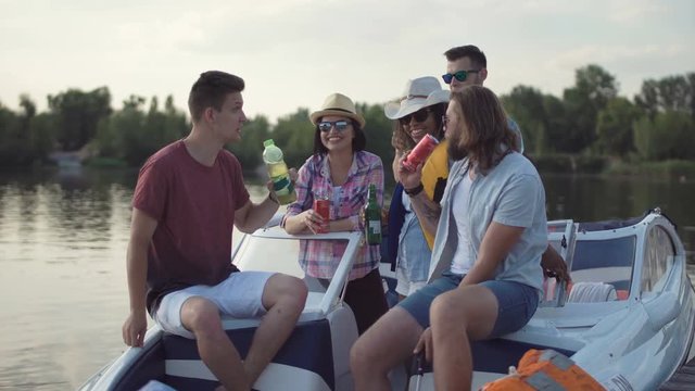 Group of diverse cheerful friends having drinks on pier near boat celebrating Independence day and make self picture with cell phone