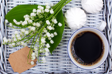 A mug of coffee, marshmallows and flowers lie on a blue wooden tray. Healthy breakfast