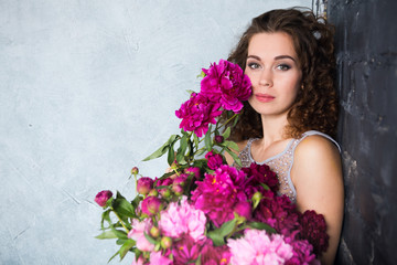 beautiful girl with pink peonies bouquet at wall. The bride with a bouquet.