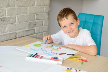 Dziecko rysuje pastelami kartkę z życzeniami dla taty. Dzień Ojca