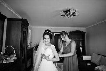 Bridesmaid helping to tie a ribbon on a wedding dress. Black and white photo.
