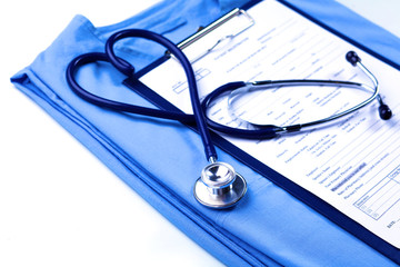 Medical stethoscope twisted in heart shape lying on patient medical history list and blue doctor uniform closeup