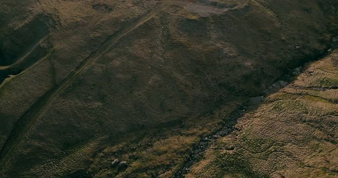 Aerial view of the wild river flows in the valley. Copter flying over the green fields. Lava mountains in Iceland.