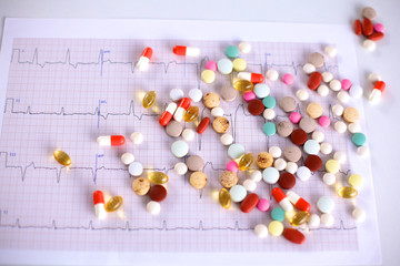 Naklejka na ściany i meble Colored pills lie on a paper cardiogram