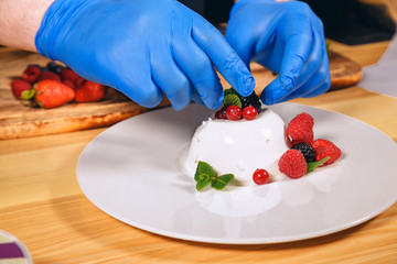 Chef hands with gloves cooked. Chef  is cooking dessert with berries.