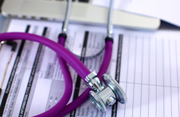 A medical stethoscope near a laptop on a wooden table, on white