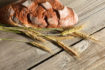 rustic crusty bread and wheat ears on a dark wooden table