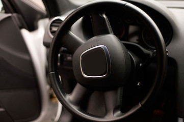balck luxury car from inside. Close up of steering wheel, seat and circuit