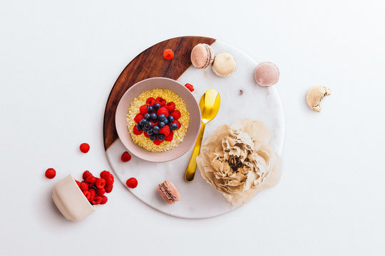 Breakfast Flatlay Scene, With Fresh Fruit, Oats, Macaroons, A Peony And A Gold Spoon, On A White Marble And Wood Board Background