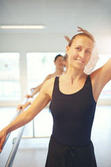 Adult woman dancing ballet looking at camera with hand up