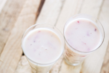Milk shake yogurt with strawberry slices on a wooden background.