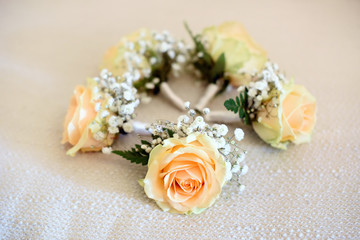 Five peach rose corsages lying in circle