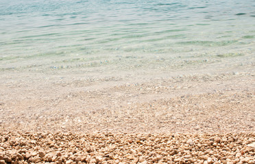 horizontal background image of calm pale blue sea on shingle beach
