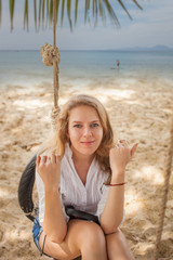 Girl sitting on the swing on the tropical beach, paradise island