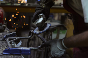 Electric wheel grinding on steel structure in a workshop with sparks flying in the air.