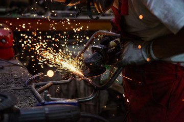 Electric wheel grinding on steel structure in a workshop with sparks flying in the air.
