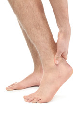 Young man suffering from pain in leg on white background, closeup