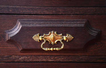 Close up view of antique metal pull knob on wooden drawer