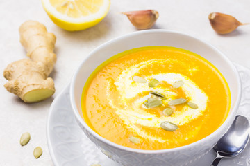 Roasted carrot ginger soup in a ceramic bowl  on stone background. 