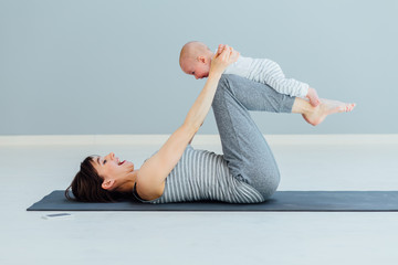 young mother does physical yoga exercises together with her baby boy