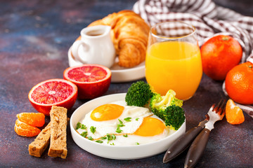 Breakfast - fried eggs with broccoli, muesli, croissant and juice on a table. Selective focus. Copy space