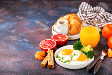 Fototapeta na wymiar Breakfast - fried eggs with broccoli, muesli, croissant and juice on a table. Selective focus. Copy space