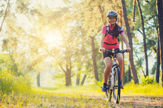 Woman Cyclist Rides In The Forest On A Mountain Bike.