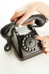 Woman's fingers dialing a vintage rotary dial telephone